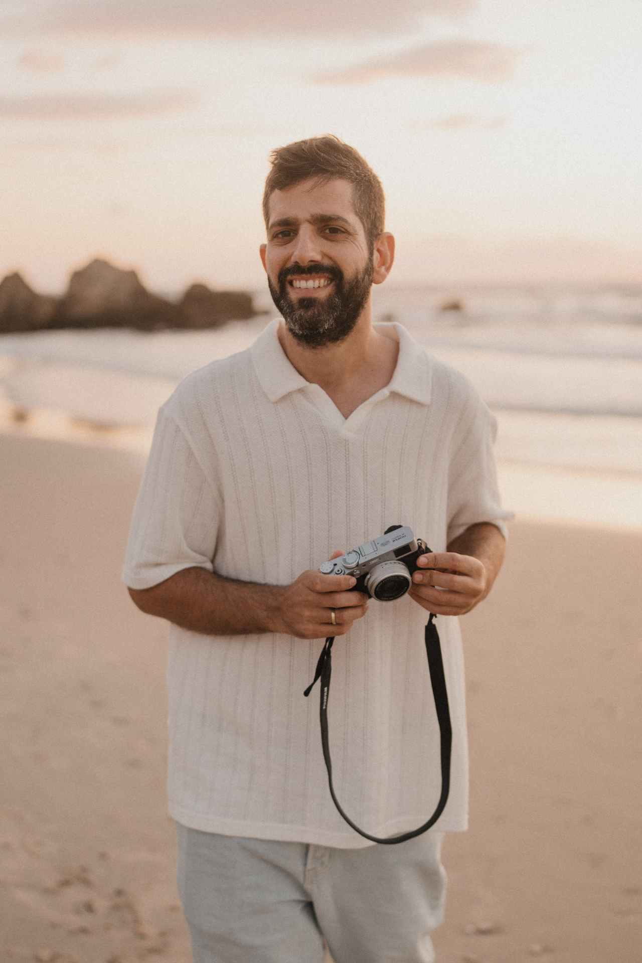 Dor Sasson on the beach at golden hour, holding his camera
